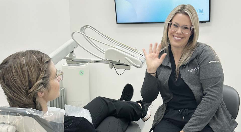 Female Patient Sitting On Dental Chair Showing Thumb And Smiling