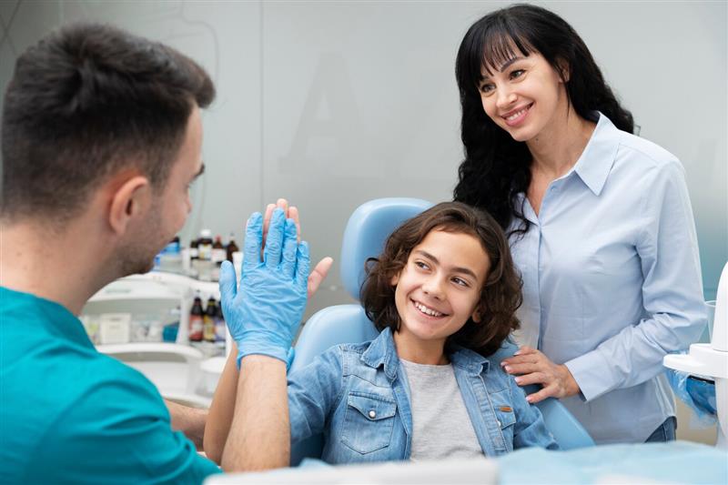 Smiling child giving a high-five to a kids dentist in Ajax during a Family Dentistry in Ajax visit with their mother.